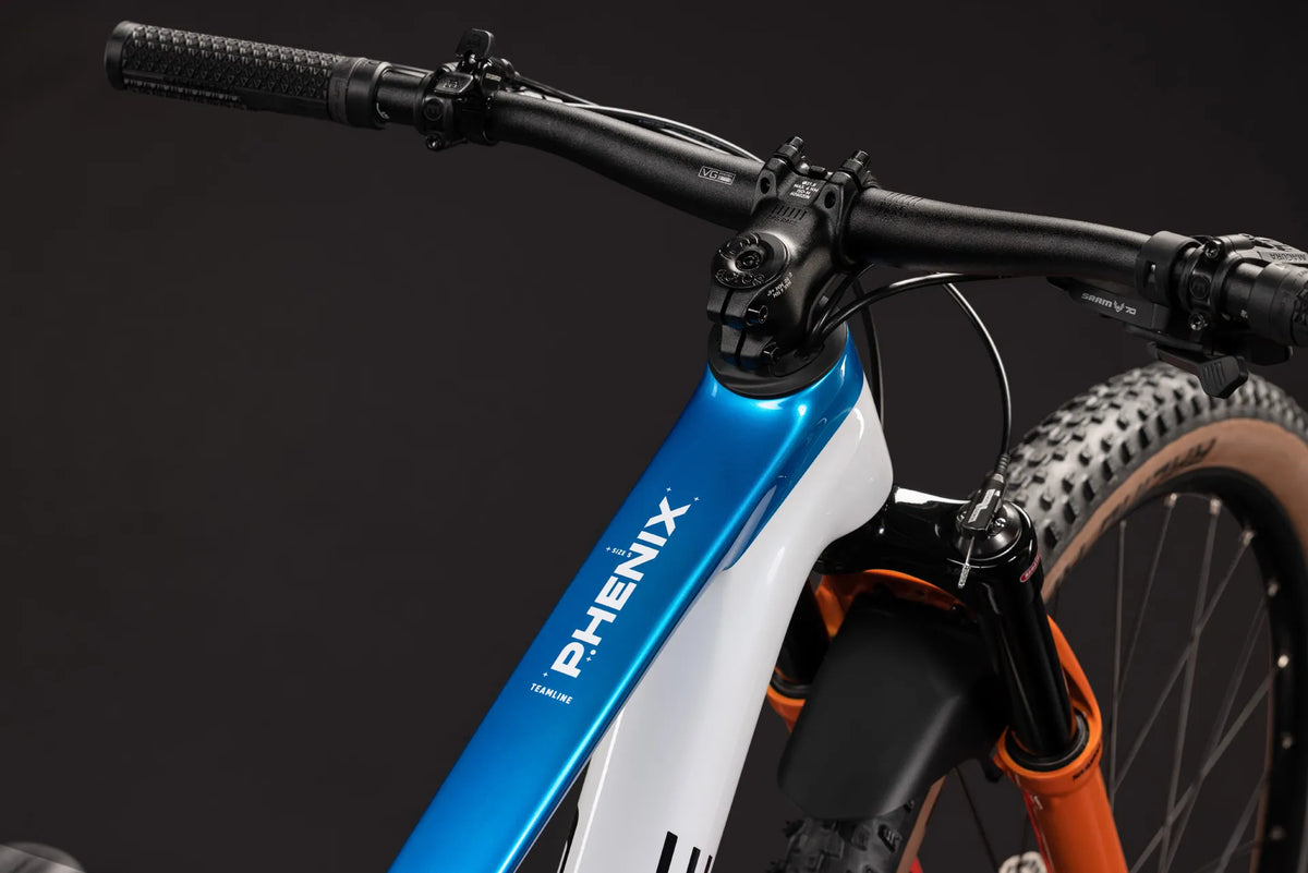 Nahaufnahme eines blauen PHENIX C:62 ROOKIE SLX
2027 Mountainbike-Rahmens mit schwarzem Lenker und Federgabel, geeignet für Offroad-Nutzung.