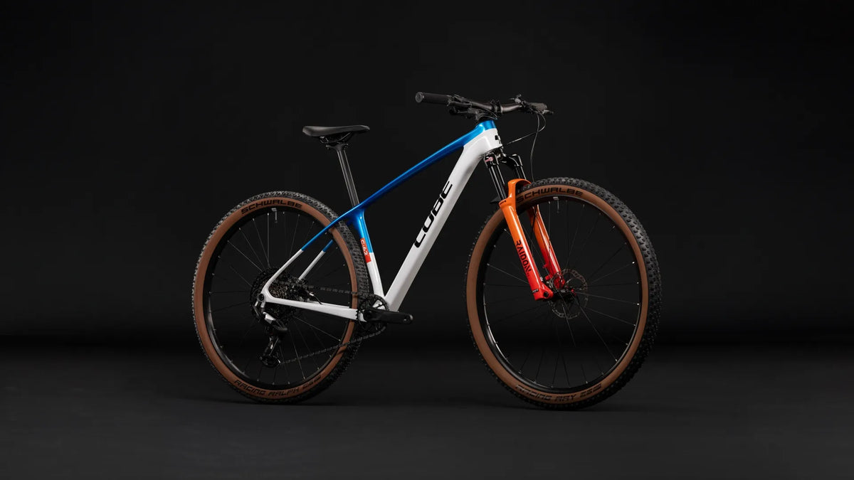 Cube PHENIX C:62 ROOKIE SLX
mit blau-weißem Rahmen, oranger Federgabel und grobstolligen Schwalbe-Reifen, geeignet für Offroad-Fahrten.
