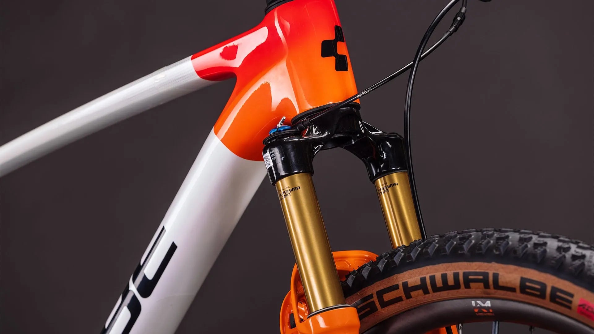 Rahmen eines Phenix C:68X SLX mit orange-weißem Design, goldene Federgabel, Schwalbe-Reifen; Markenname Cube sichtbar.