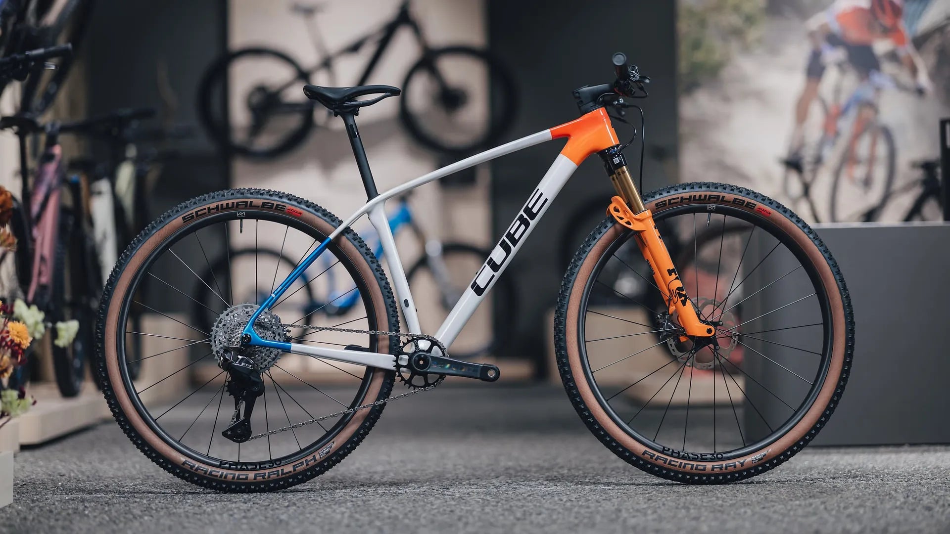 Mountainbike Phenix C:68X SLX in Weiß und Orange, geeignet für Geländefahrten, ausgestellt in einem Fahrradgeschäft.
