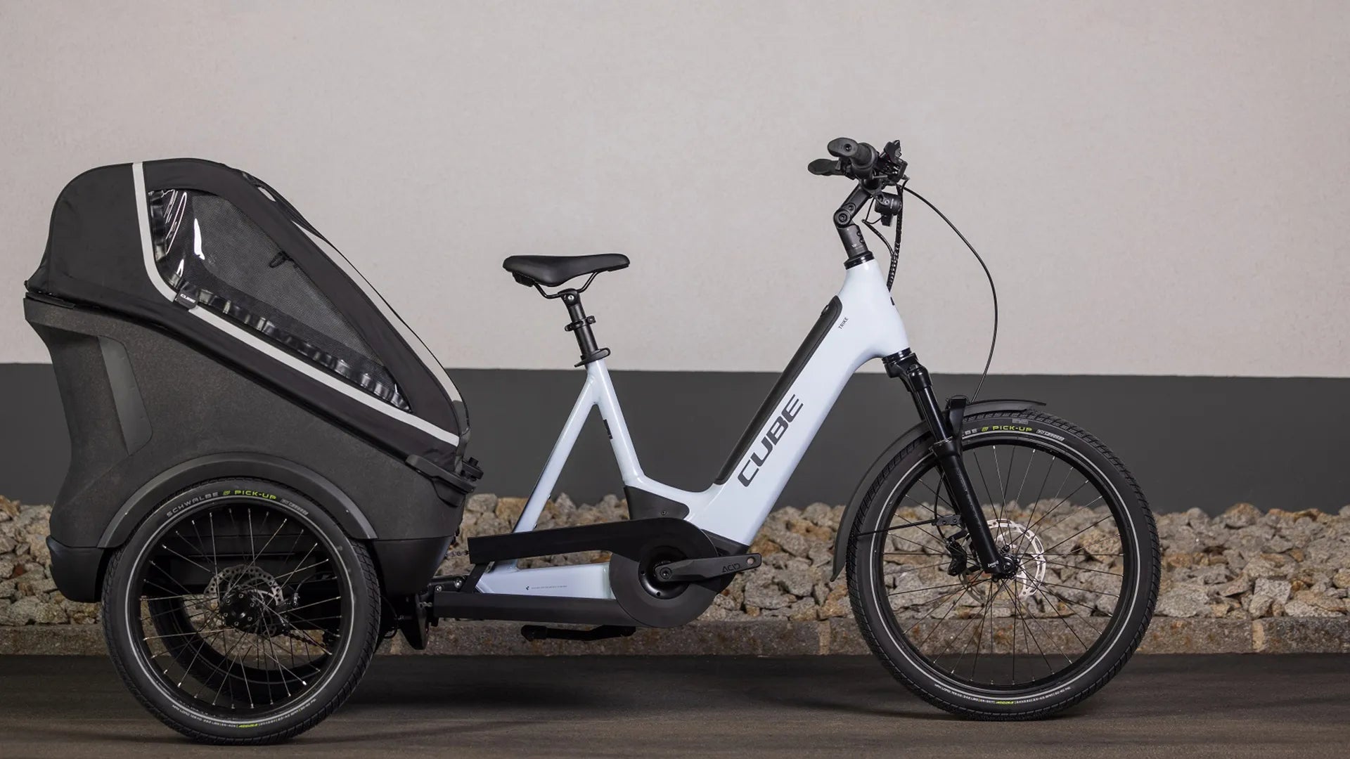 Weißes CUBE TRIKE FAMILY HYBRID 750 mit großem schwarzen Transportanhänger, ideal für urbanen Transport und Familien.